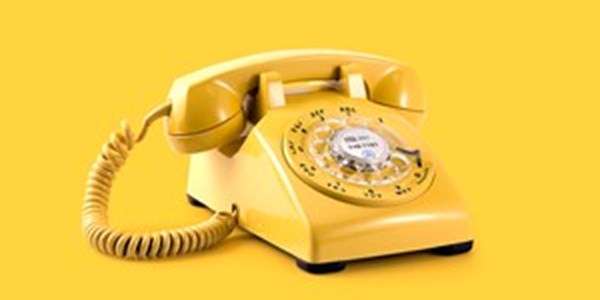 A yellow old fashioned dial telephone