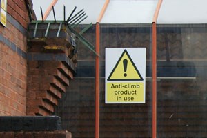 An anti climb notice attached to a high fence surounding a building