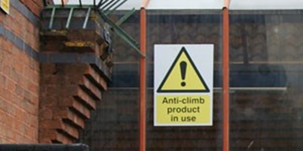An anti climb notice attached to a high fence surounding a building