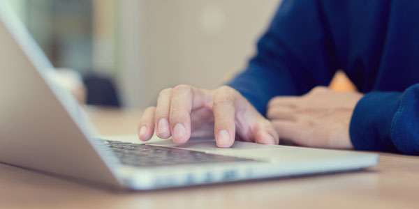 A hand hovering over a track pad of a laptop
